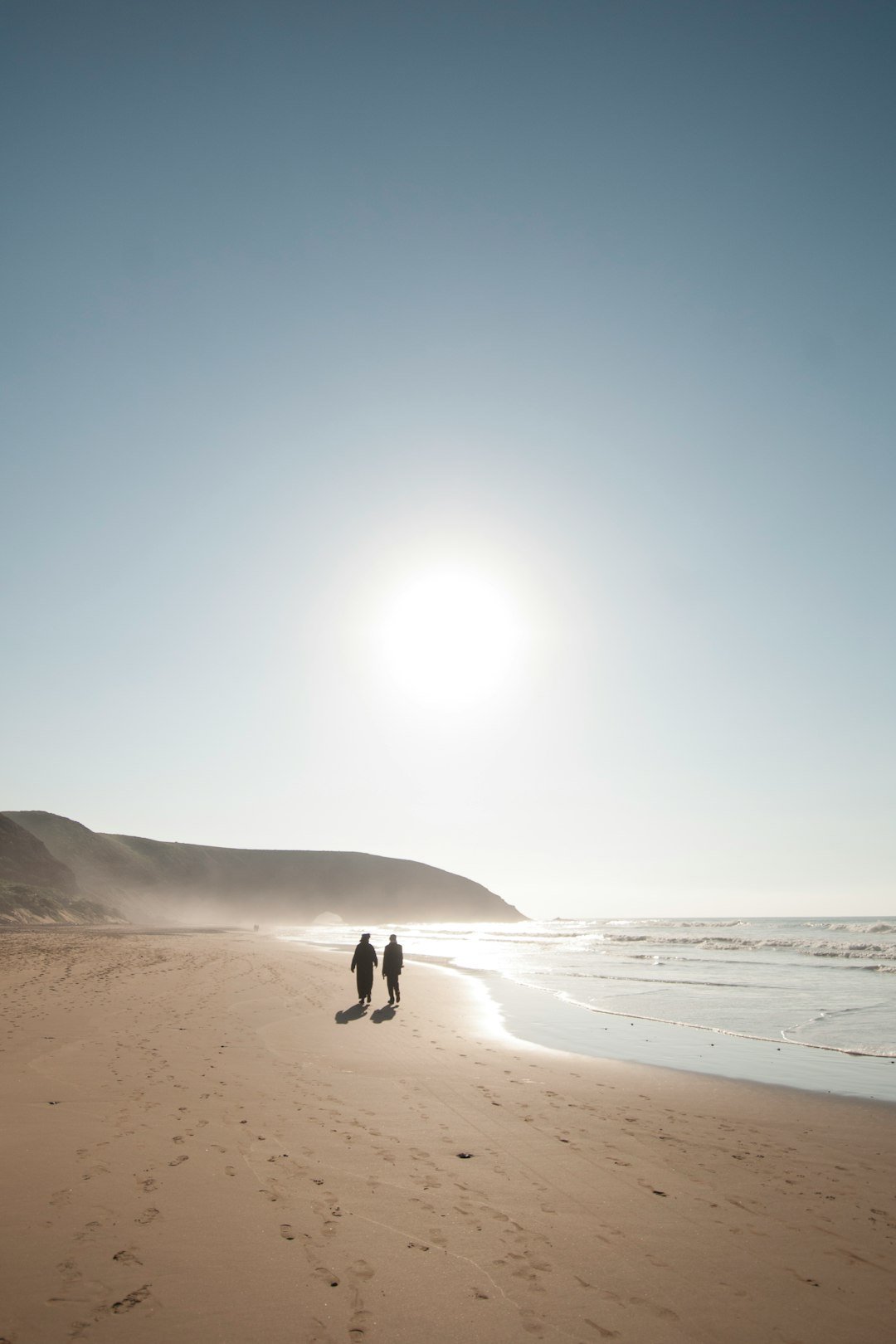 two person walking on shore